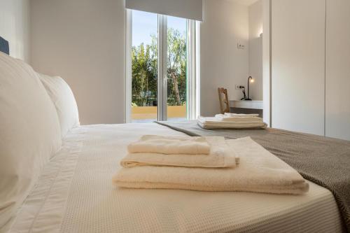 a bedroom with white towels on a bed with a window at QSF Agro Turismo Quinta da Sagrada Família in Évora