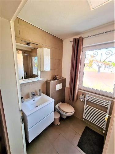 a bathroom with a sink and a toilet and a window at Apartment Villa Engel with Pool in Poreč