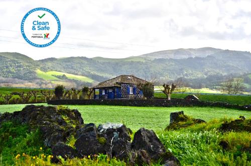 a blue house in a field with mountains in the background at Casa da Canada in Ribeira Grande