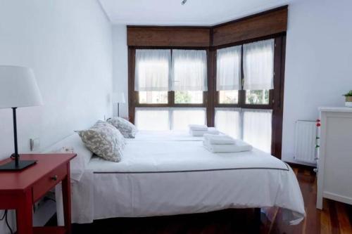 ein Schlafzimmer mit einem weißen Bett und einem Fenster in der Unterkunft EL BALCÓN DE CAMPO LOS PATOS in Oviedo