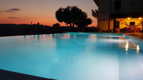 a large swimming pool with a sunset in the background at B&B A Robba de Pupi in Agrigento