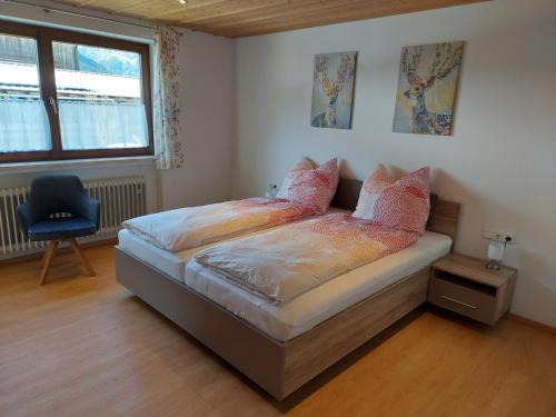 een slaapkamer met een bed met een stoel en een raam bij Fewo Sonnenberg Graswang in Graswang