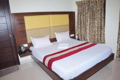 a bedroom with a large white bed with a yellow headboard at B2B Home Stay in Kodaikānāl