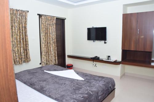 a bedroom with a bed and a flat screen tv at B2B Home Stay in Kodaikānāl