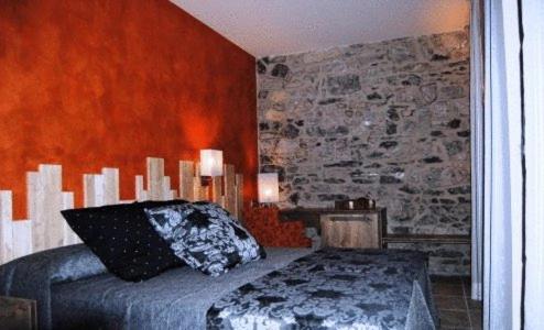 a bedroom with a bed and a stone wall at Santa Bárbara in Sant Corneli de Cercs 