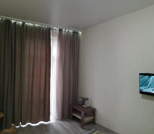 a room with a window with curtains and a table at Апартаменты на Соборном с видом на парк in Zaporozhye
