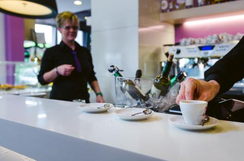 a person holding a cup of coffee on a counter at Hotel Calaluna in Musile di Piave