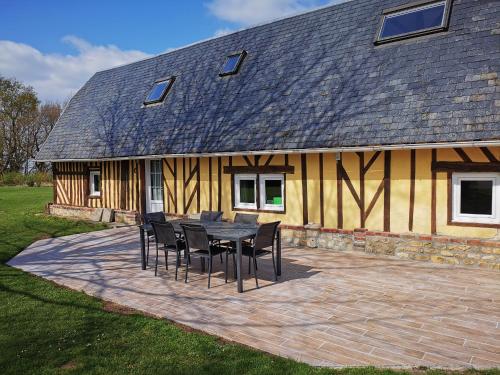 une table et des chaises devant une maison dans l'établissement La Bergerie, à Cambremer