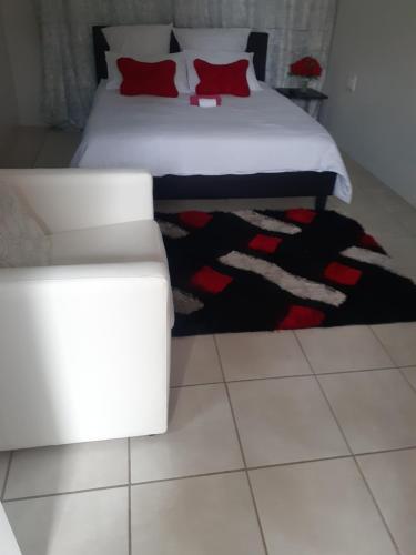 a bedroom with a white bed and a white couch at Ruros Guest House in Kempton Park