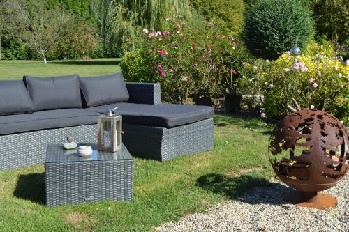 a couch and a table in a garden at Un Air de Campagne in Couloisy