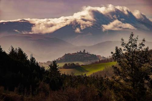 una vista su un castello su una collina con un cielo nuvoloso di La vedetta del Montefeltro a Peglio