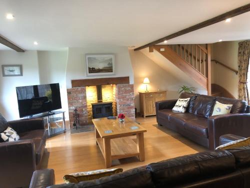 a living room with a couch and a table and a fireplace at Great Coombe, Bookham Court in Dorchester