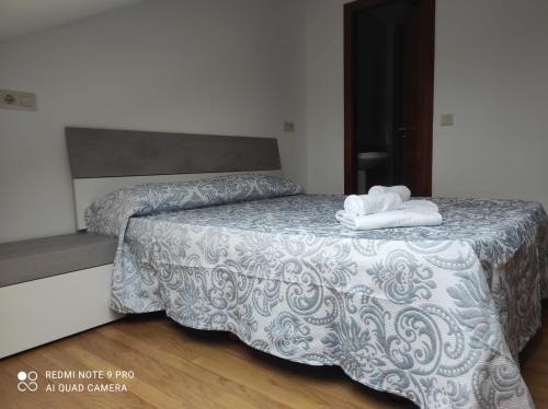 Atico Cuntis Thermae في Cuntis: غرفة نوم عليها سرير وفوط