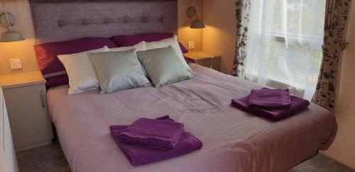 a bed with purple towels on top of it at Port Haverigg Marina Village in Millom