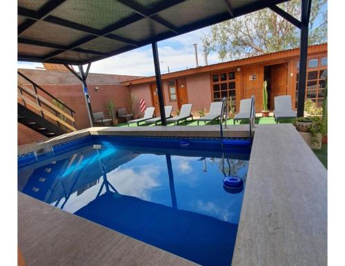 a swimming pool with chairs and a house at Hostal Alto Yalí in San Pedro de Atacama