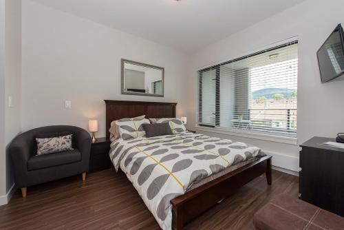 a bedroom with a bed and a chair and a window at Lower Lonsdale Aprtment in North Vancouver