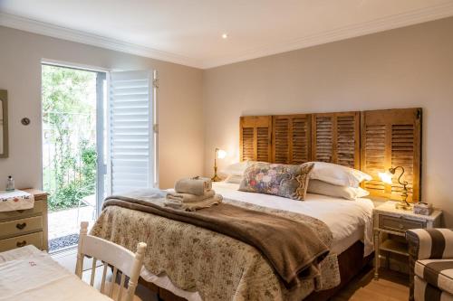 a bedroom with a large bed with a wooden headboard at Nerf-af ROOMS at Onrus , Hermanus in Hermanus