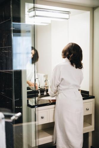 a woman standing in front of a sink in a bathroom at Rosewood Hotel Georgia in Vancouver