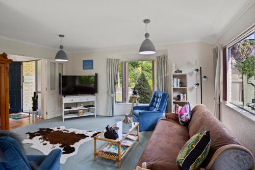 a living room with a couch and a tv at Fantails Roost - Bowentown Holiday Home in Waihi Beach