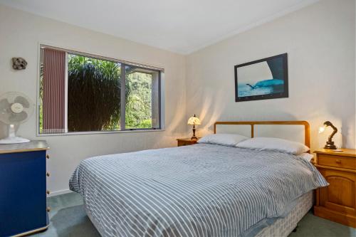 a bedroom with a bed and a window at Fantails Roost - Bowentown Holiday Home in Waihi Beach