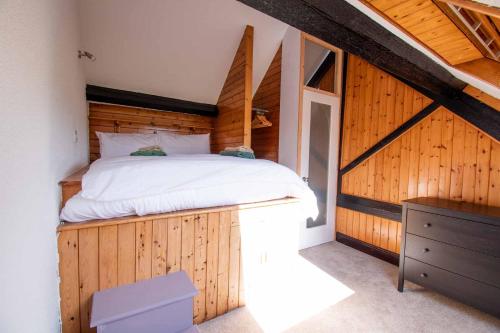 a bedroom with a bed on a wooden wall at Long Byres Holiday Cottages in Brampton