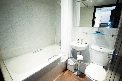 a bathroom with a sink and a toilet and a bath tub at Long Byres Holiday Cottages in Brampton