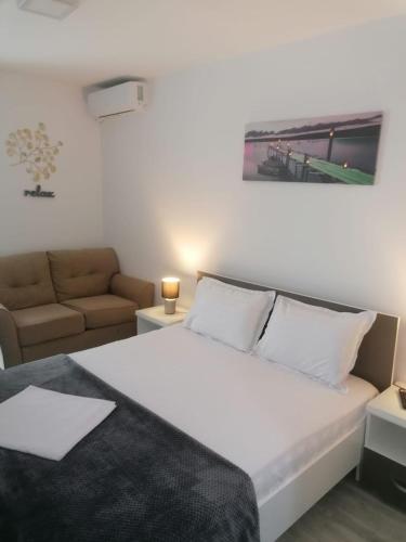 a bedroom with a large white bed and a couch at Alfa Relax Apartments in Saturn