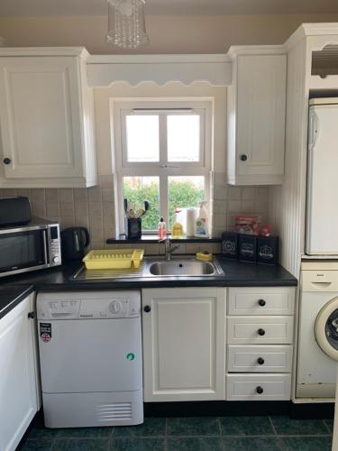 a kitchen with white cabinets and a sink and a window at Mayfield House Holiday home in Ballinrobe