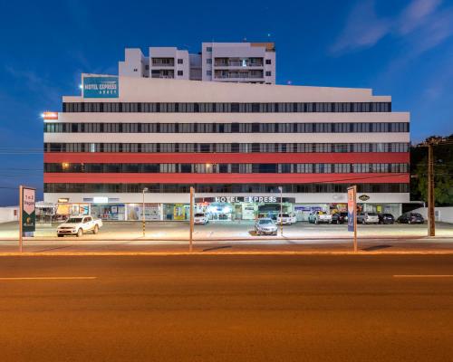 un gran edificio con coches estacionados en un estacionamiento en Hotel Express Arrey - Teresina en Teresina