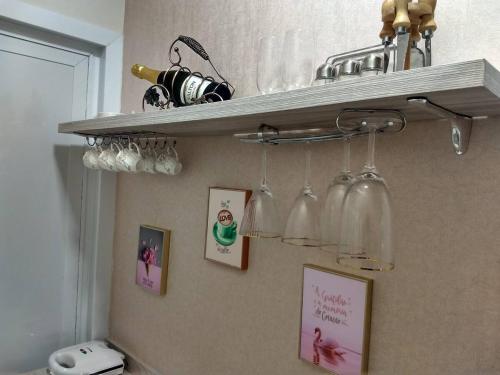 a kitchen with a shelf with wine glasses and pictures at Cantinho da Florzinha in Foz do Iguaçu