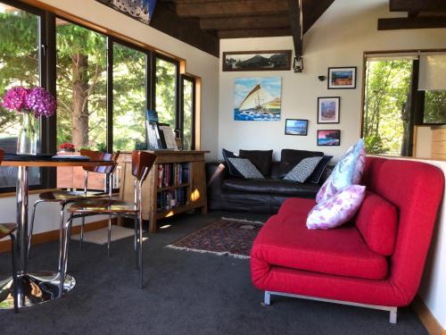 a living room with a red couch and a table at Crows Nest - Queenstown Holiday Home in Queenstown