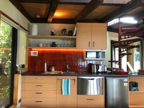 a kitchen with wooden cabinets and stainless steel appliances at Crows Nest - Queenstown Holiday Home in Queenstown