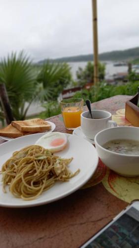a table with a plate of spaghetti and a bowl of soup at Baan Dongsak River view in Sangkhla Buri