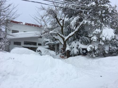 a yard covered in snow next to a house at HA-MON Slope Side Hotel and Private Chalet in Otari