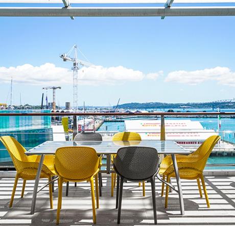 a table and chairs on a balcony with a view of a boat at Auckland Waterfront Serviced Apartments on Prince's Wharf in Auckland