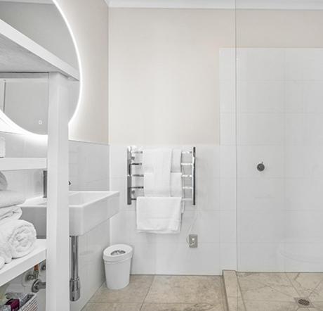 a white bathroom with a shower and a sink at Auckland Waterfront Serviced Apartments on Prince's Wharf in Auckland