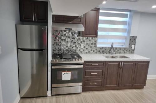 Una cocina con refrigerador de acero inoxidable y estufa. en Prestige Accommodation Self-contained 2 Bedrooms Suite, en Ajax
