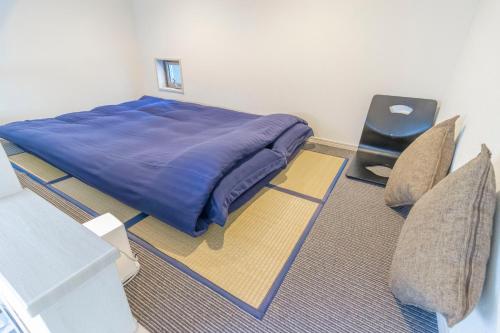 a bedroom with a blue bed and two chairs at japan house Ikebukuro in Tokyo
