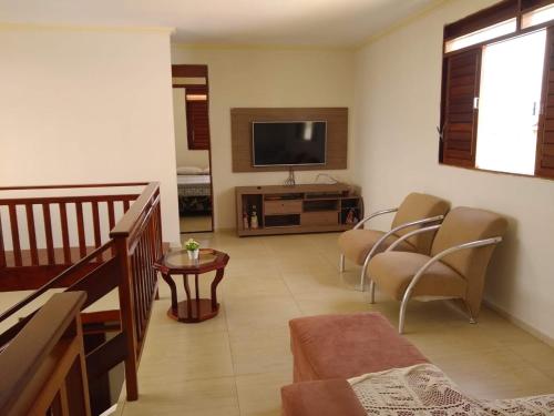 a living room with a flat screen tv and chairs at Cond. Águas da Serra, Bananeiras in Bananeiras