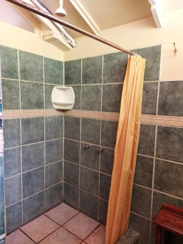 a shower with an orange shower curtain in a bathroom at Cabina Rancho la Merced in Uvita