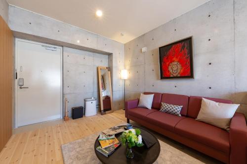 a living room with a red couch and a table at Tamatsukuri Daifuji Kan in Osaka
