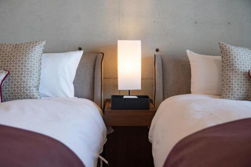 a hotel room with two beds and a lamp at Tamatsukuri Daifuji Kan in Osaka