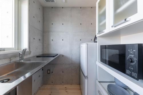 a small kitchen with a sink and a refrigerator at Tamatsukuri Daifuji Kan in Osaka