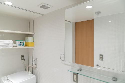 a bathroom with a toilet and a mirror at Tamatsukuri Daifuji Kan in Osaka