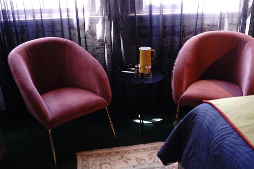 two pink chairs sitting next to a table with a drink on it at The Intrepid Hotel in Wellington