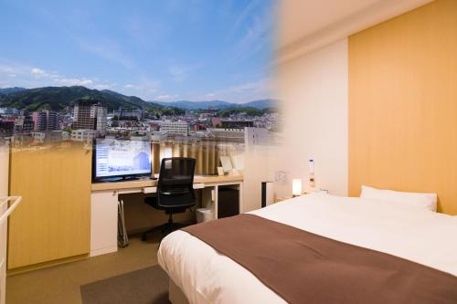 1 dormitorio con 1 cama y escritorio con ordenador en Spa Hotel Alpina Hida Takayama en Takayama