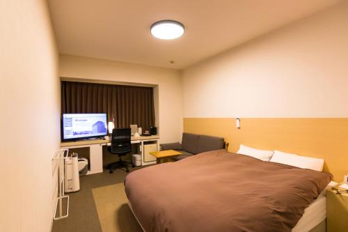 a bedroom with a bed and a desk with a computer at Spa Hotel Alpina Hida Takayama in Takayama