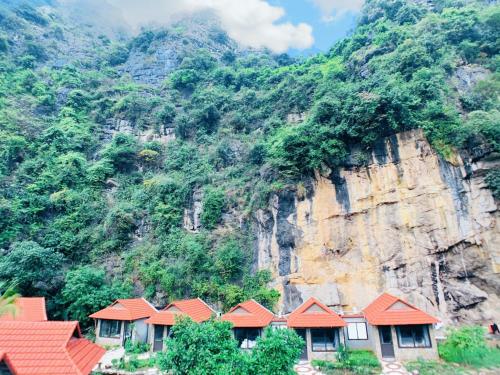 a row of houses with red roofs in front of a mountain at Trang An Peaceful Homestay in Ninh Binh