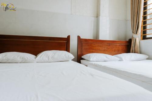 two beds with white pillows sitting next to each other at SH Hotel in Hue