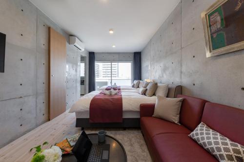 a bedroom with a large bed and a red couch at Tamatsukuri Daifuji Kan in Osaka